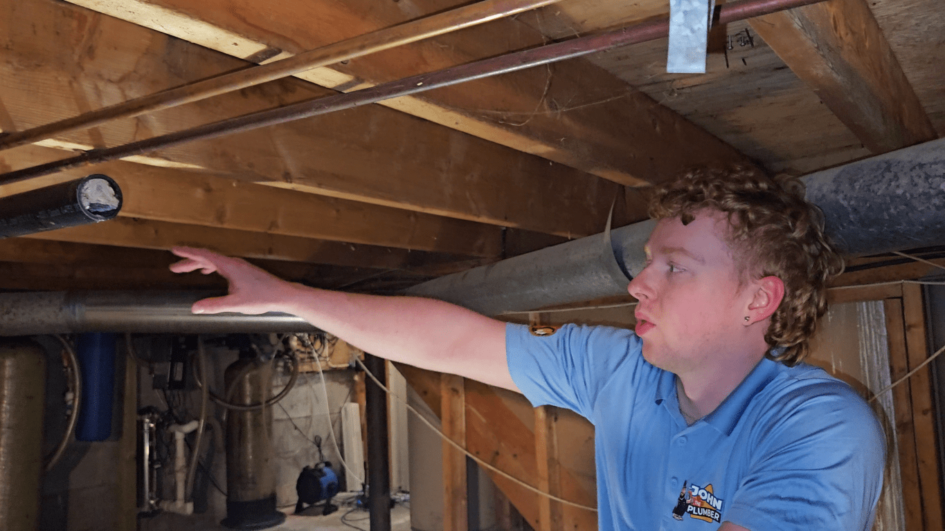 Plumber inspecting accessible pipes and plumbing connections in an Ottawa home