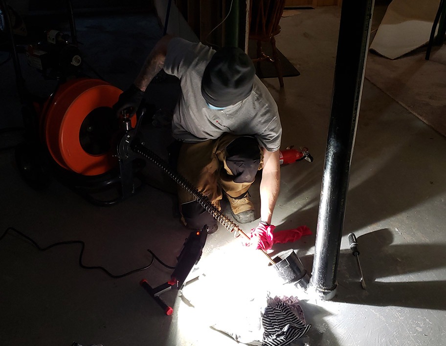 Plumber using a drain snake to clear a clogged drain in Ottawa