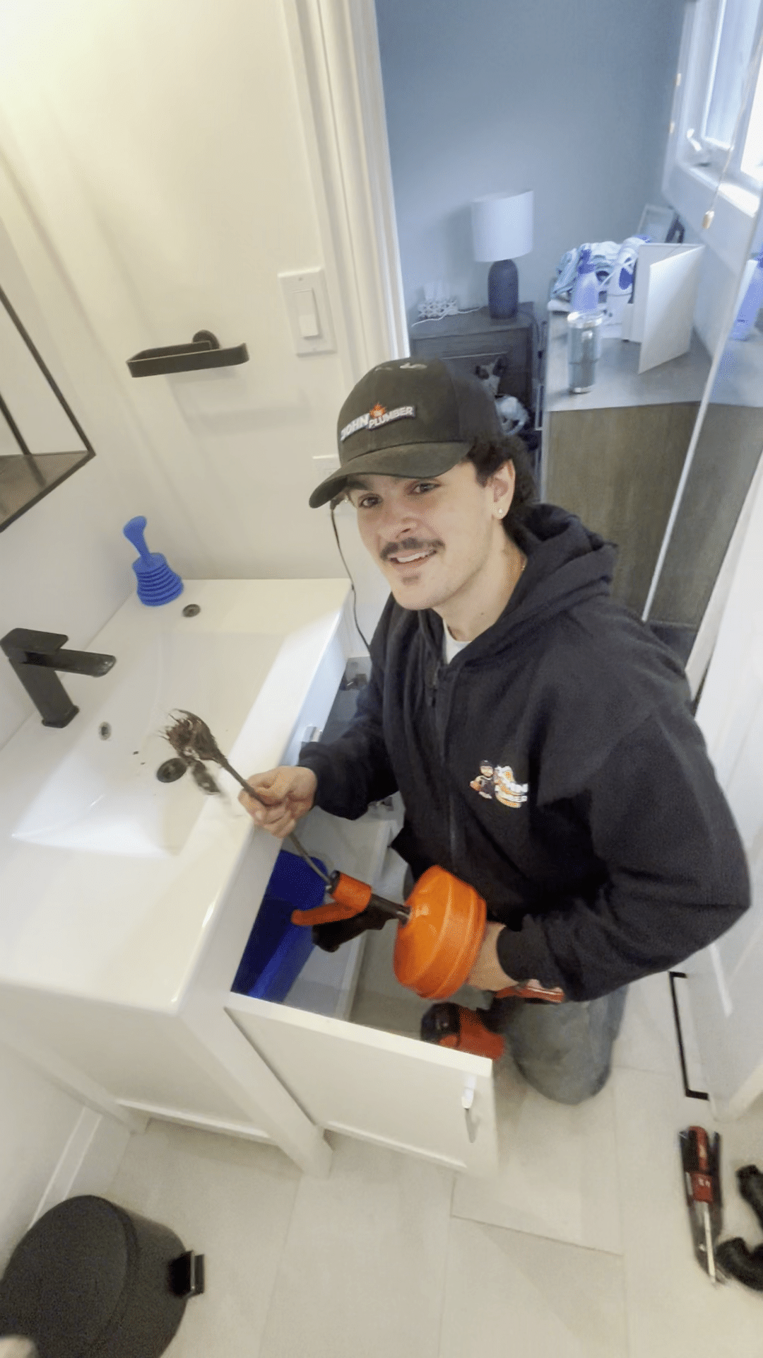 Plumber holding clog removed while snaking a bathroom sink drain at KiWi Condos
