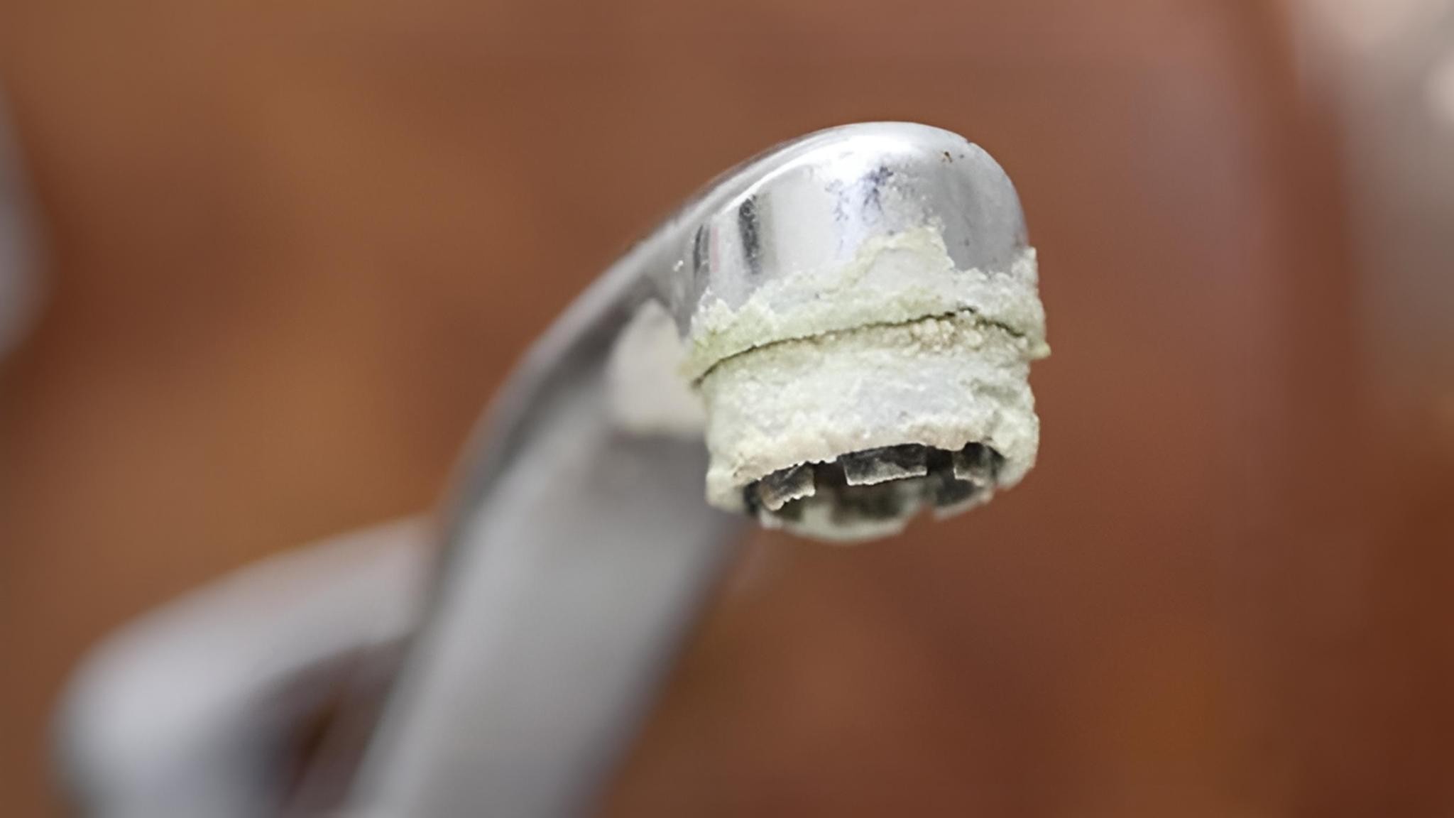 Heavy white calcium and limescale buildup around a chrome faucet aerator