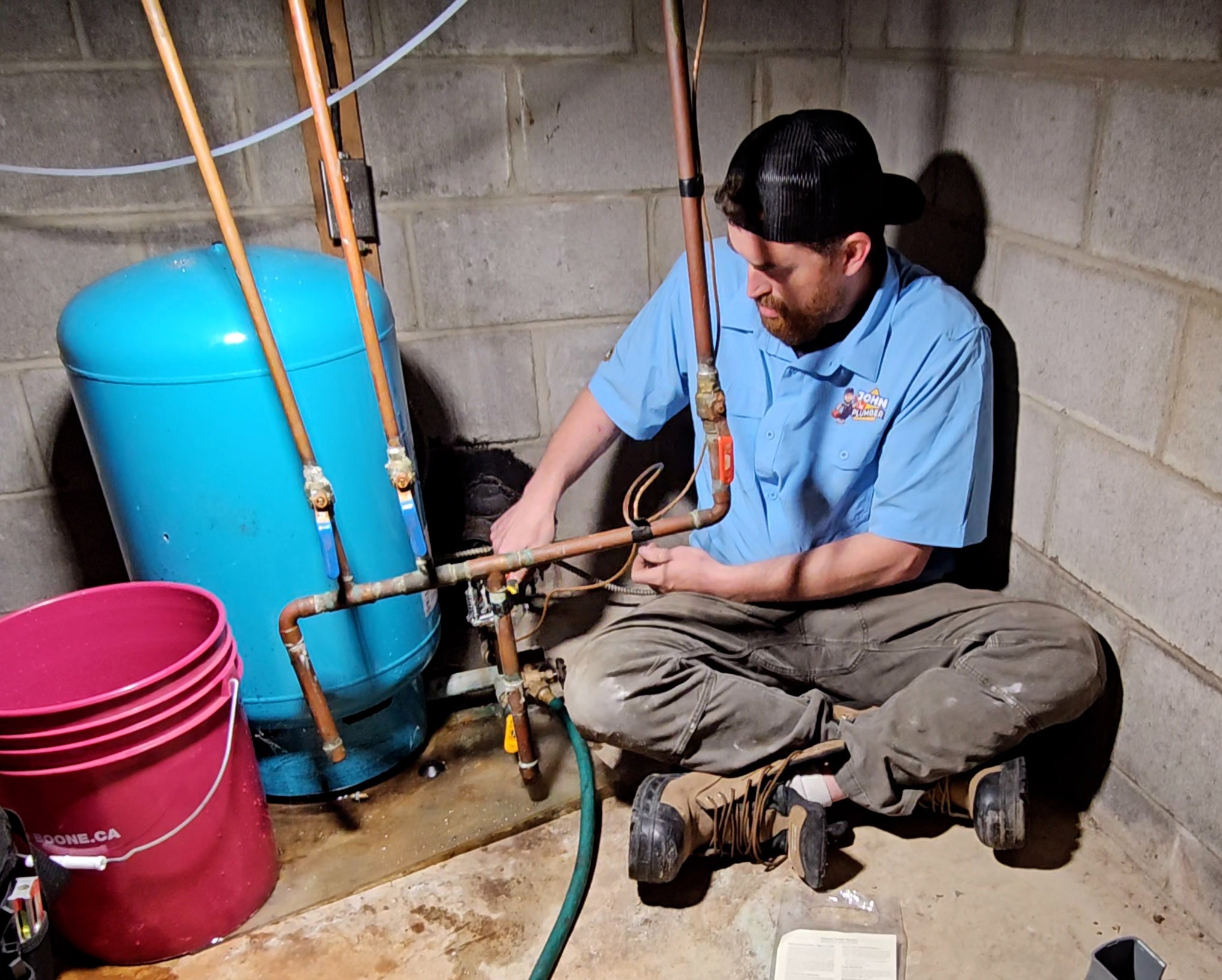 John The Plumber technician working on piping and controls beside a residential well pressure tank