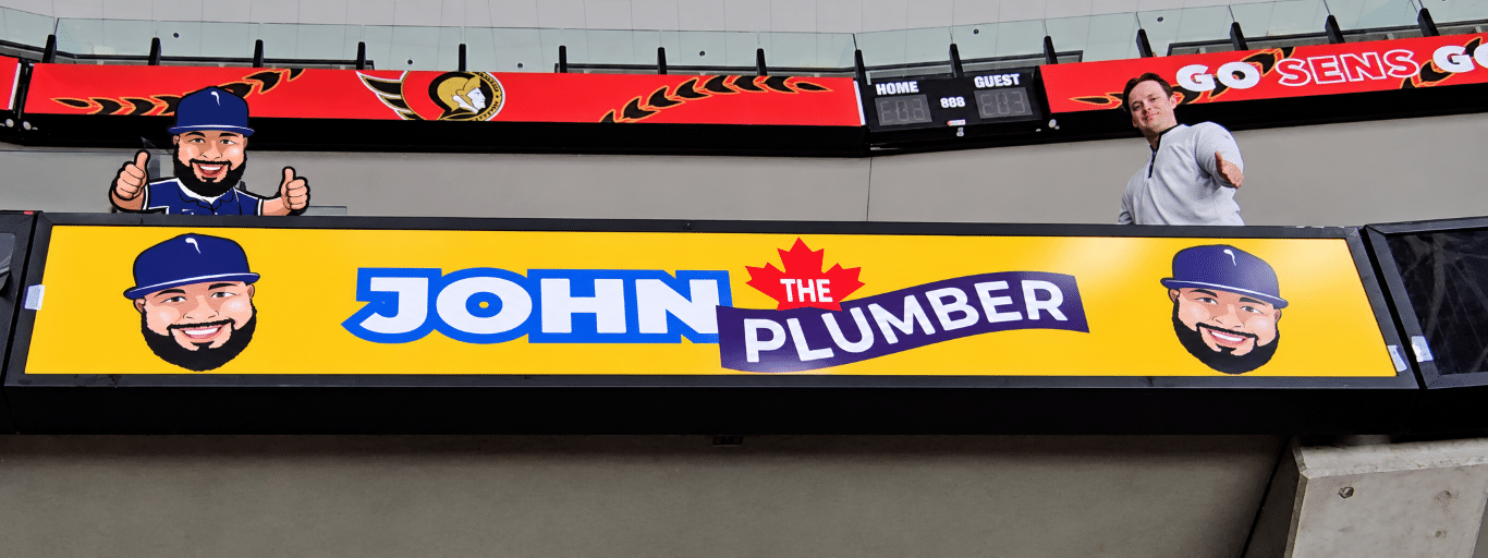 John The Plumber arena advertising at an Ottawa Senators game, with a bright yellow rink-side sign and Sens signage overhead