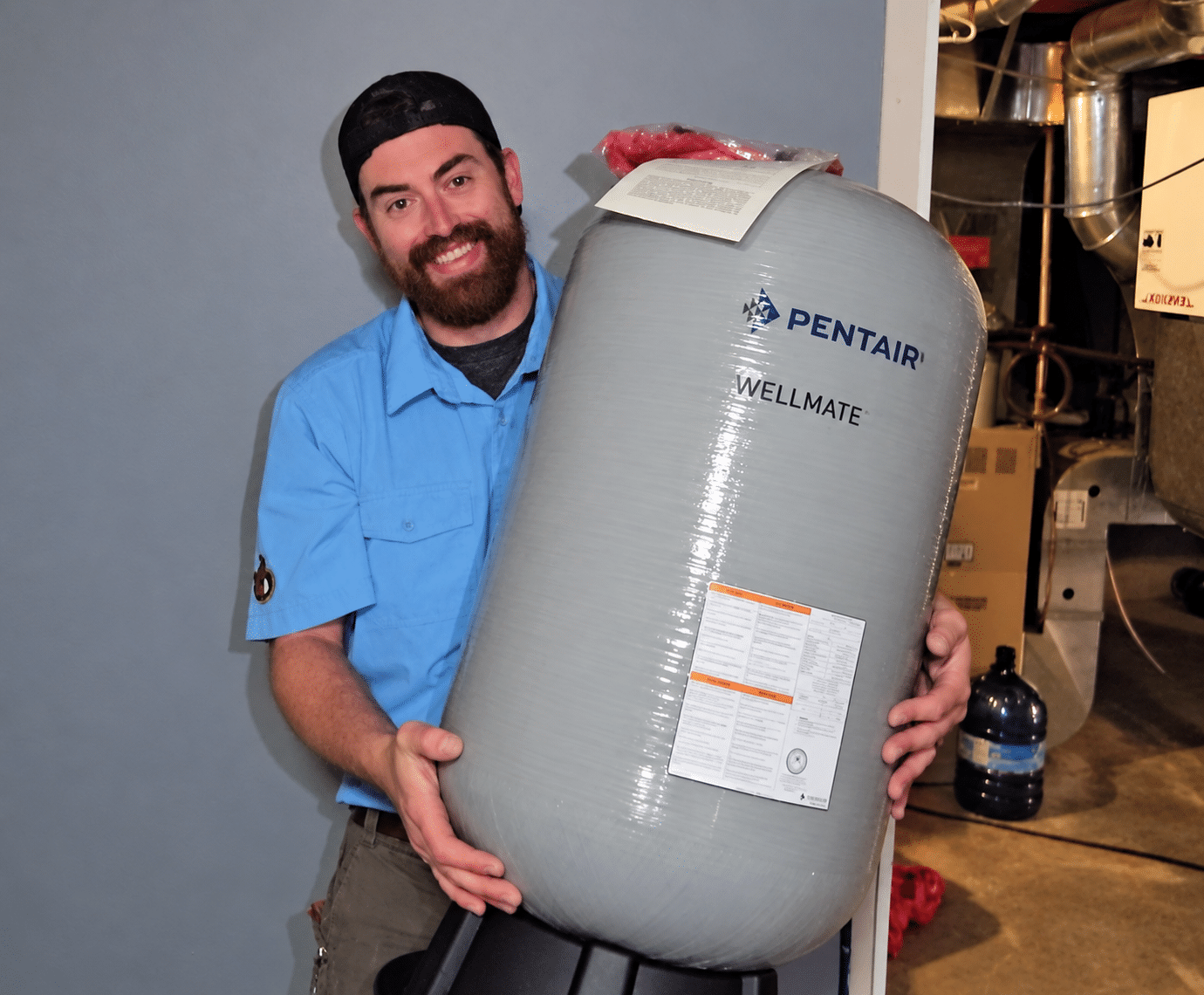 John The Plumber team member holding a residential well pressure tank in Ottawa